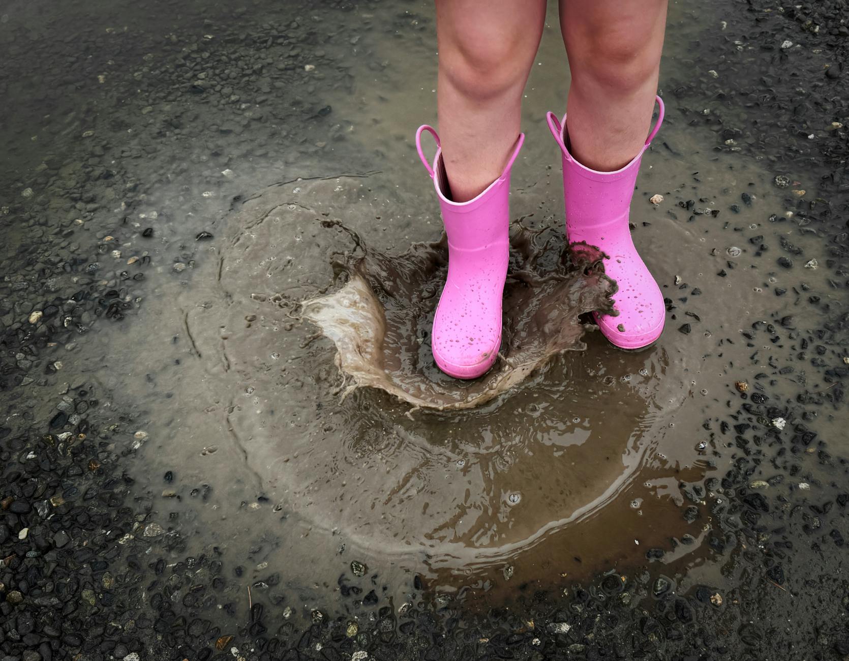 child enjoying rainy day in pink boots