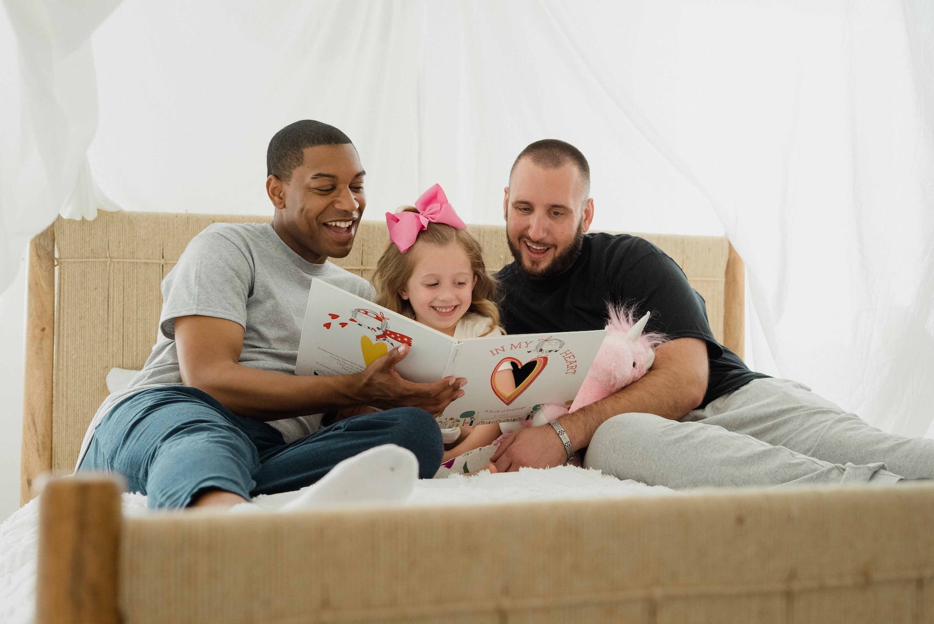 photograph of parents reading a book with their daughter