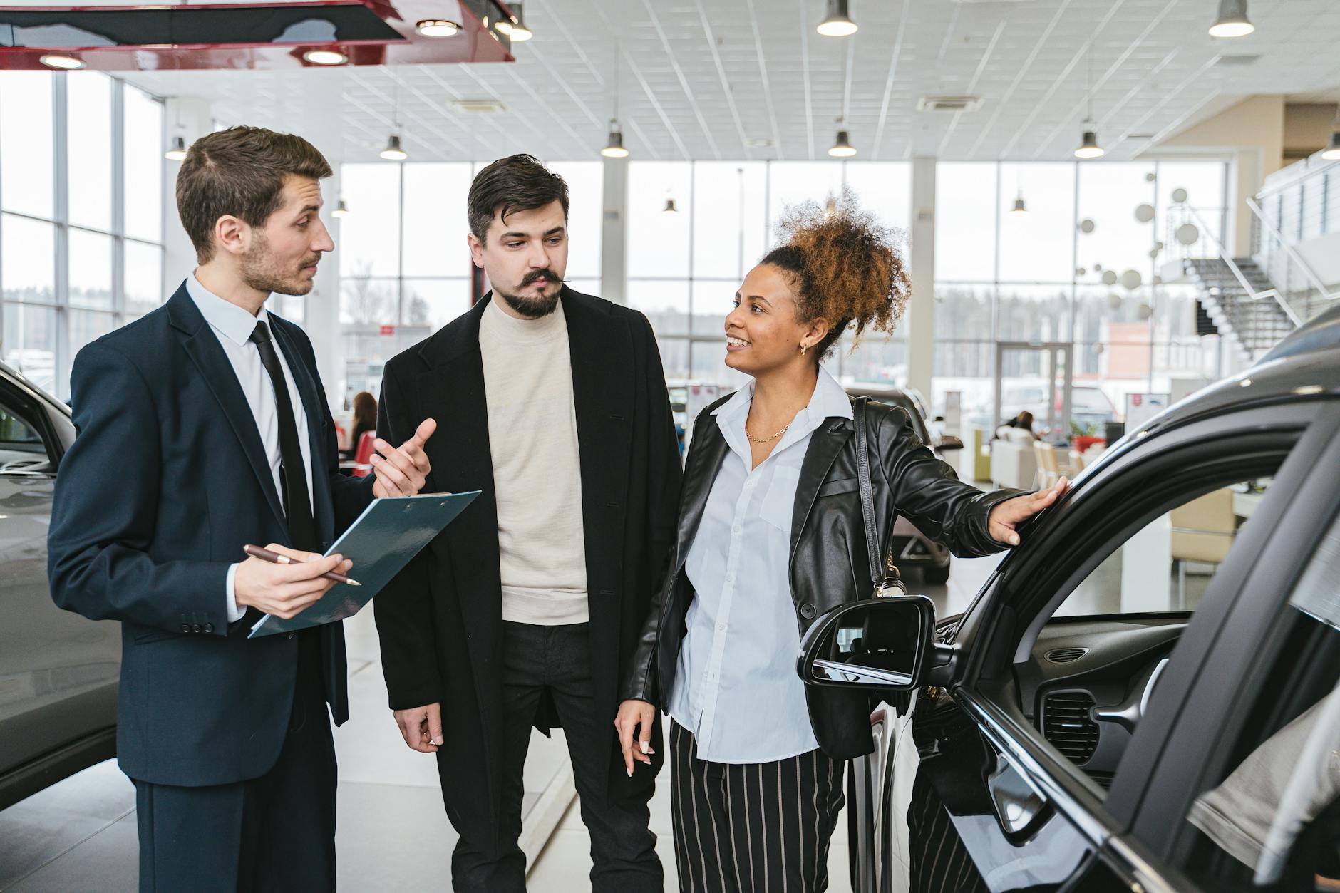 man in blue business suit talking to woman touching the car