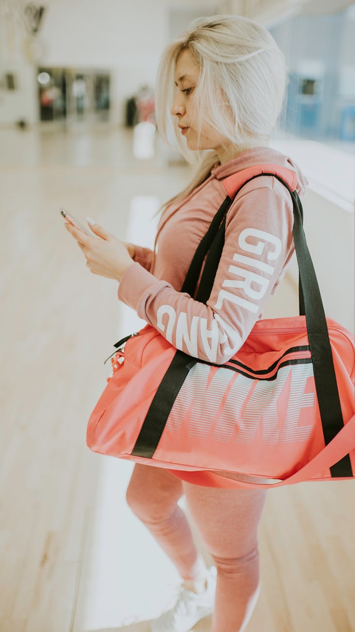 a woman using a mobile phone while carrying a duffle bag