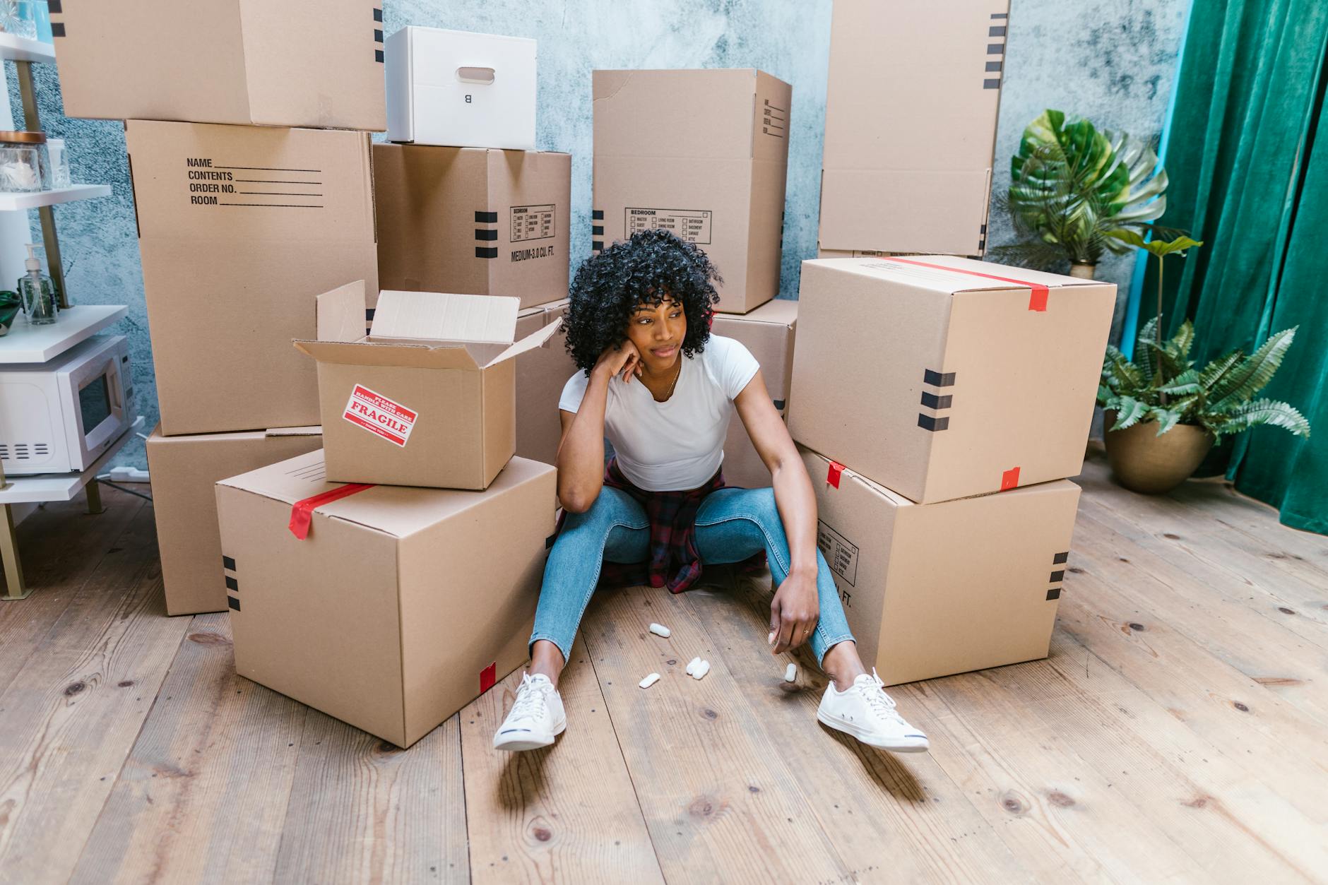 close up shot of a woman sitting on the floor near cardboard boxes