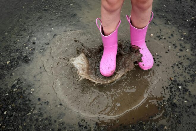 child enjoying rainy day in pink boots